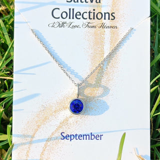 Necklace with a blue pendant on a branded card with grass background