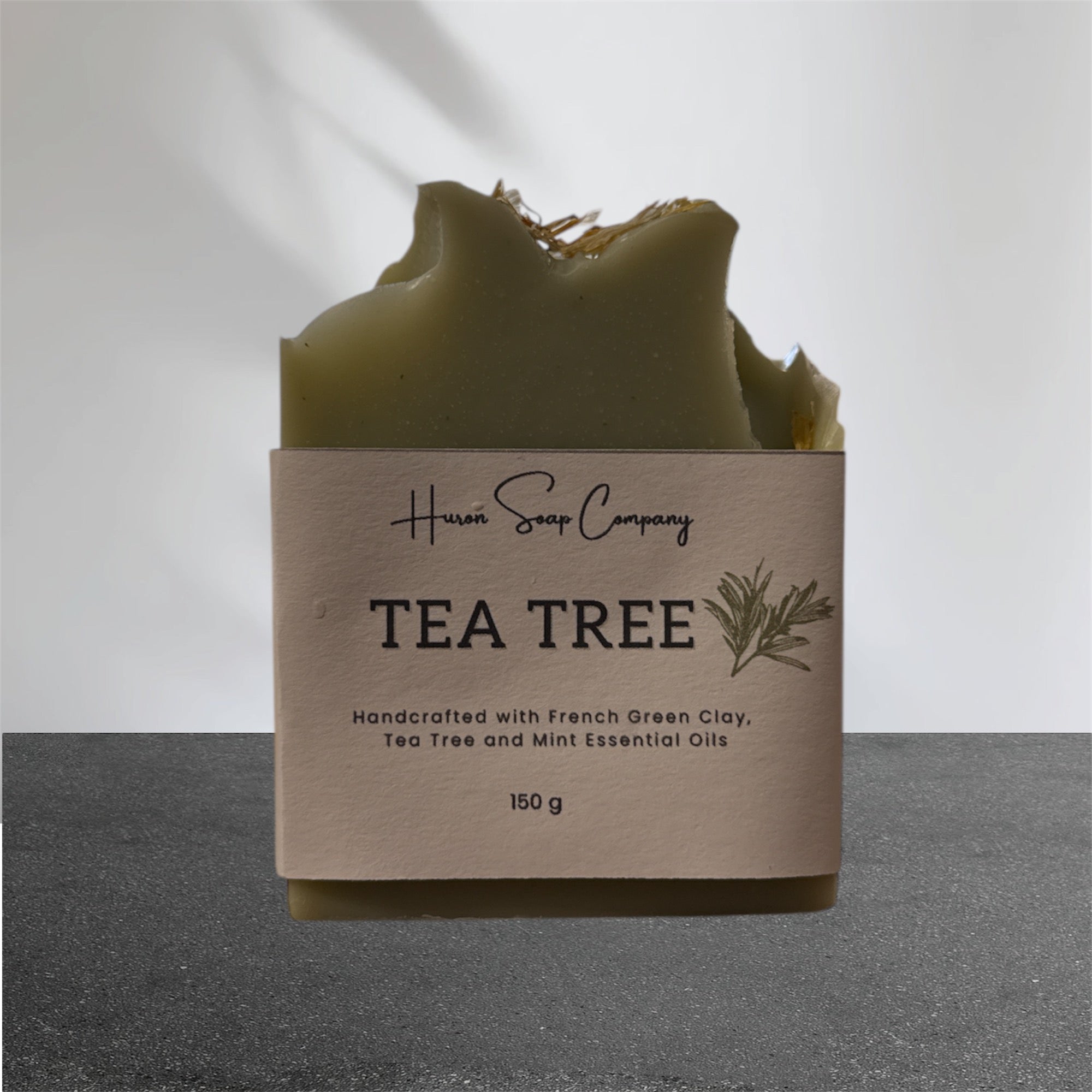 Tea tree artisan soap with packaging from Huron Soap Company on a gray background