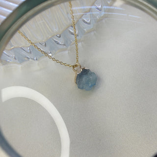 Necklace with a blue gemstone under a magnifying glass on a light background