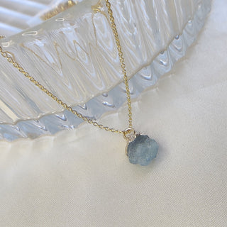 Necklace with a blue gemstone pendant on a white background