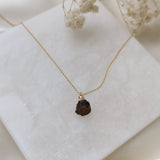 Necklace with a dark pendant on a white surface