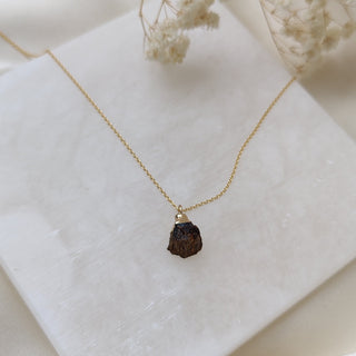 Necklace with a dark pendant on a white surface